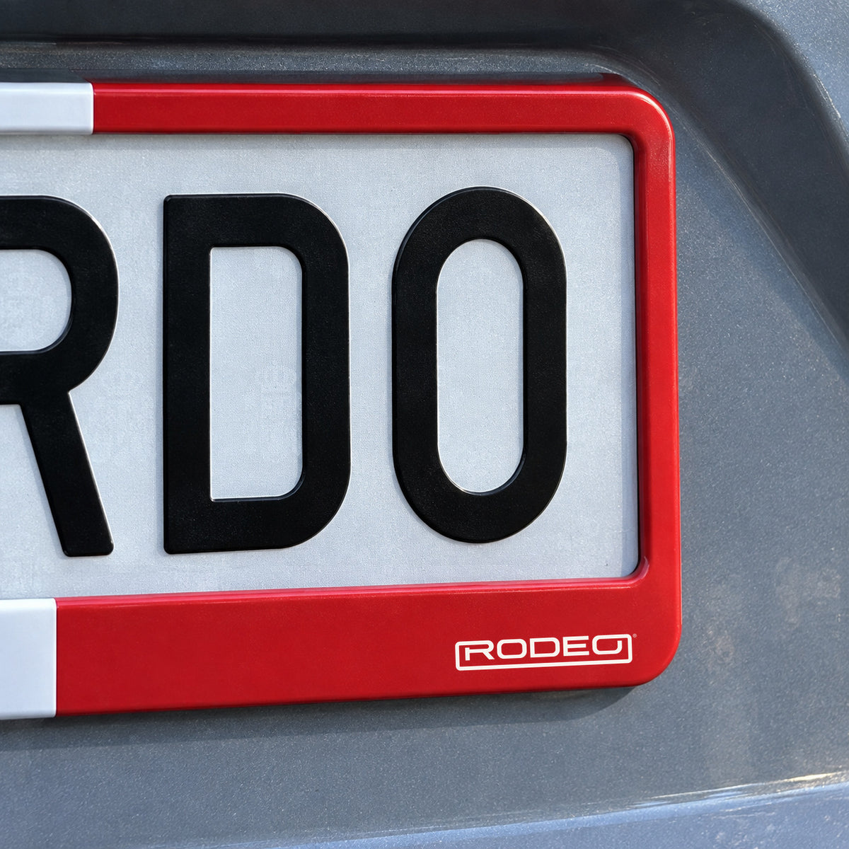 Detalle del logo Rodeo blanco sobre la esquina roja del portamatrículas Francia.