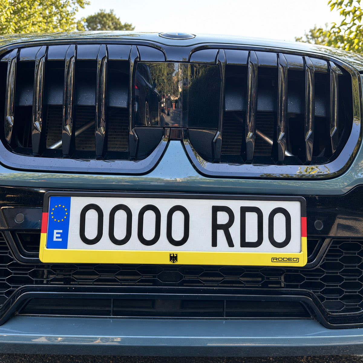 Portamatrículas Rodeo Alemania instalado bajo la parrilla delantera de un BMW X1 verde, con escudo central.