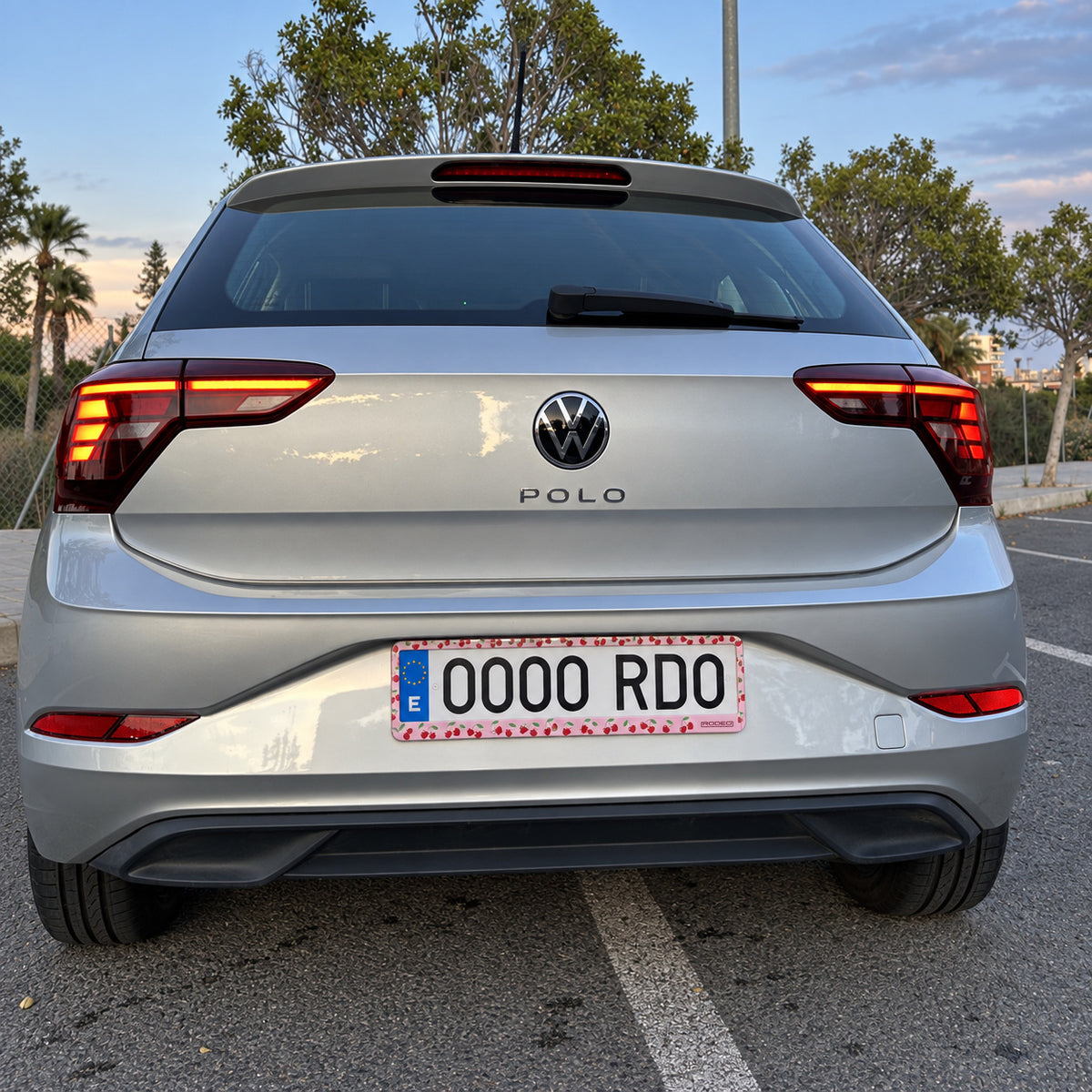 Portamatrículas Rodeo Cerezas instalado en la trasera de un Volkswagen Polo plateado al atardecer.