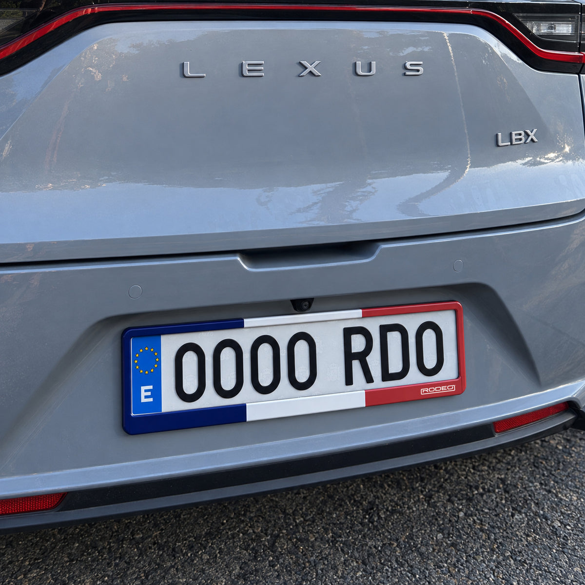 Portamatrículas Rodeo Francia instalado en la trasera de un Lexus LBX gris, visto en ángulo.